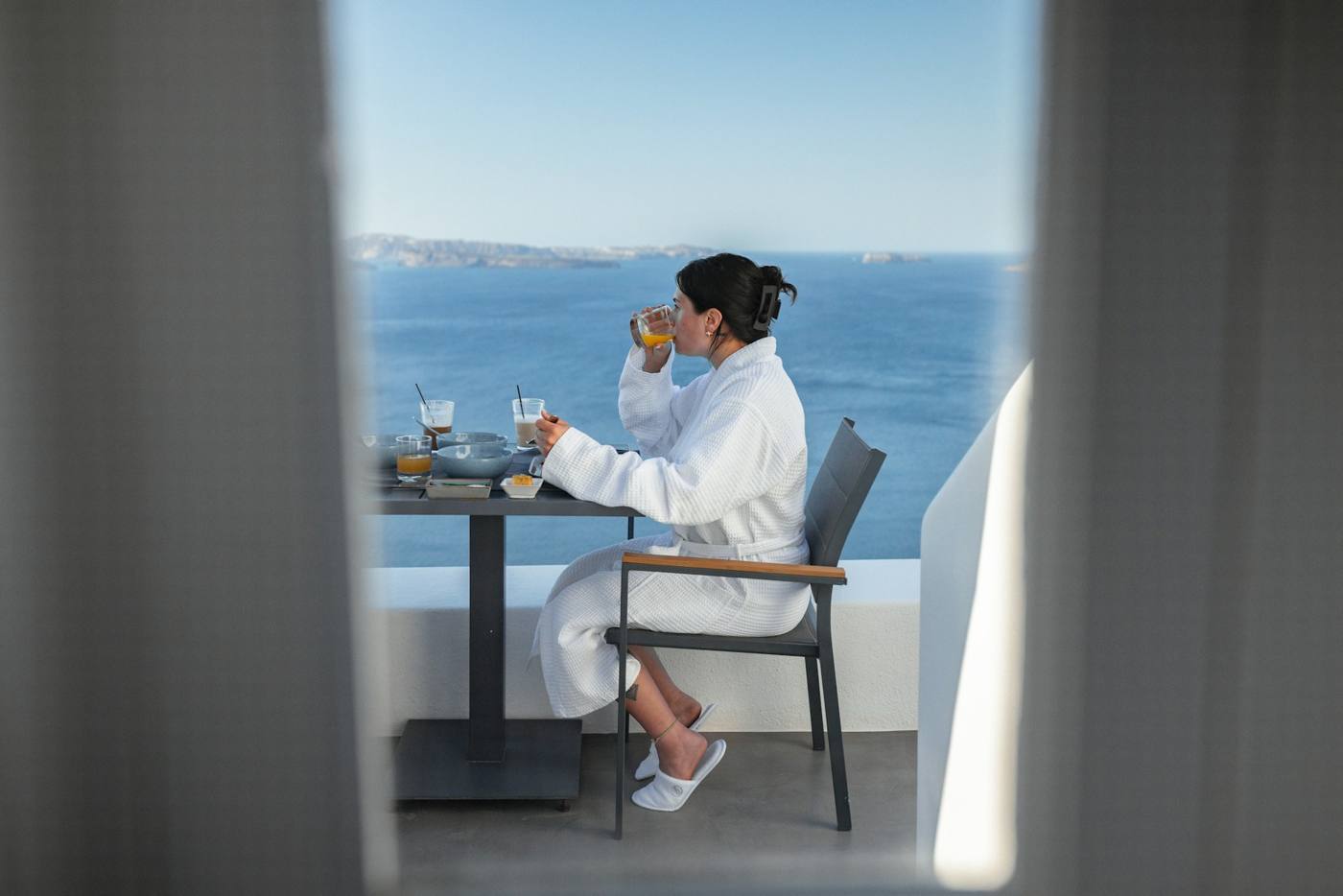Mujer desayunando tranquila en un balcón frente al mar